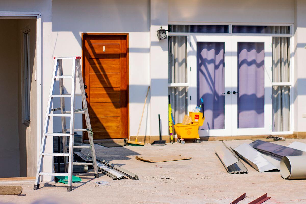 Hus under ombyggnad med byggmaterial vid entrén